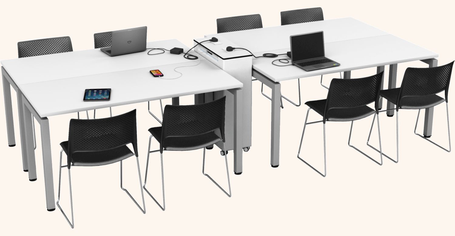Ein weißer Zioxi Ladewagen integriert zwischen vier weißen Konferenztischen mit schwarzen Stühlen, an denen Laptops, ein Tablet und ein Smartphone aufgeladen werden.